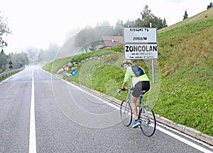 Sporty boy pedaling with the cycling bike and the sign indicating the locality Zoncolan in northern Italy very famous for cycling