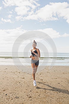 Sporty brunette woman jogging on the beach