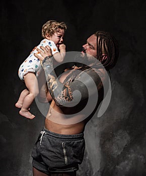 Sporty brutal man holds in arms a little baby