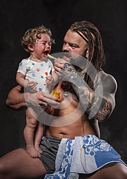 Sporty brutal man holds in arms a little baby