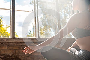 Sporty calm woman sit in lotus pose doing yoga meditating in sunny gym