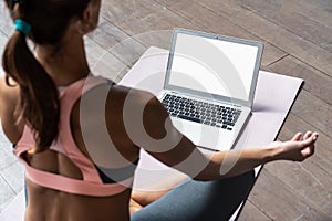 Sporty calm woman sit on mat watch online yoga class on laptop mock up screen