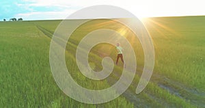 Sporty child runs through a green wheat field. Evening sport training exercises at rural meadow. A happy childhood is a