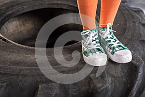 Sporty child in sportswear standing on tire at fitness studio