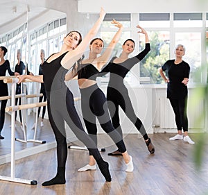Brunette performing battement tendu at group barre fitness training photo