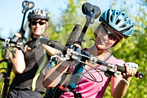 Sporty couple carrying their mountain bikes