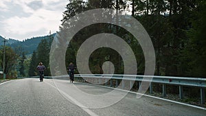 Sporty couple cycling forest on highway road. Travelers riding bike in mountains
