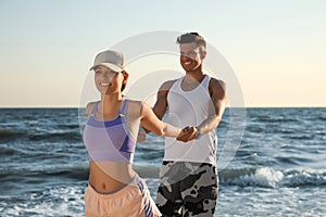 Sporty couple doing exercise on beach at sunset