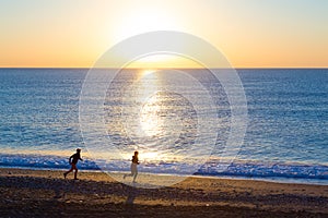 Sporty Couple doing Morning Jogging on Sea Beach at Sunrise