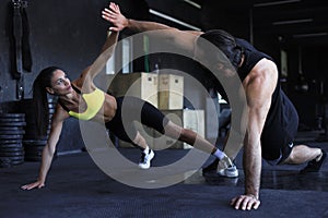 Sporty couple doing push ups and giving high five to each other in gym