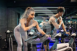 Sporty couple doing spinning on cycle bike indoors.