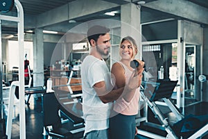 Sporty couple exercising dumbbell weights lifting in fitness gym., Portrait of attractive young couple are practicing workout in