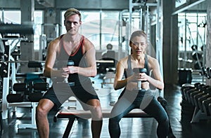 Sporty couple man and woman exercise with dumbbells or does the exercises at gym