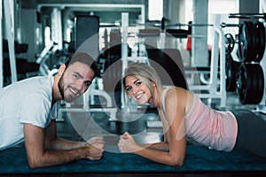 Sporty couple planking exercise in fitness gym., Portrait of attractive young couple are practicing workout in training class., photo