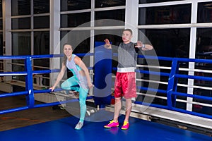 Sporty couple standing near blue corner of a regular boxing ring