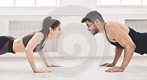 Sporty couple standing in plank in front of each other