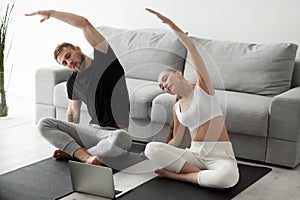 Sporty couple stretching watching fitness video tutorial online