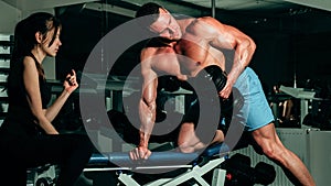Sporty couple. Woman trainer with muscular man doing functional training workout doing biceps lifting dumbbell