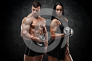 Sporty couple working out on wall background. Muscular man and woman