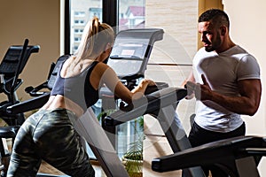 Sporty couple workout cardio exercise gym. Sportive couple in gym. Personal trainer fitness instructor helping woman