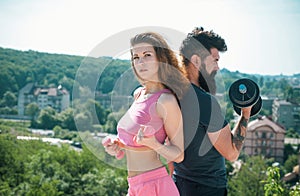 Sporty couple workout with dumbbells. Muscular man and woman training arms workout using heavy dumbbells. Sporty woman