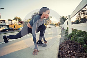 A sporty dark skin girl stretching in the bike path in the city