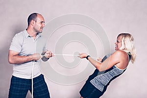 Sporty determined woman and man pulling a rope
