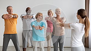 Sporty elderly people having fitness class, training with instructor photo