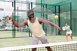 Sporty emotional man playing doubles paddle tennis