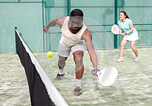 Sporty emotional man playing doubles paddle tennis