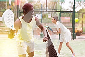 Sporty emotional man playing doubles padel game