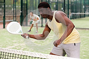 Sporty emotional man playing doubles padel game