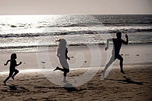 Sporty family father, mother and baby son running together. Child with parents run by water along sea. Sport, health and