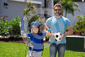 Sporty family. Little kid learning to ride bicycle with father in park. Father teaching son cycling. Father and son