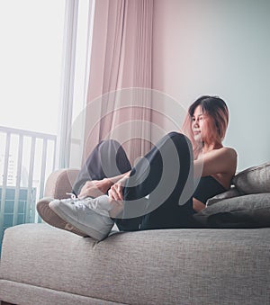Sporty Fashion model girl is posing with white sneakers shoes on Sofa in an apartment for cool street sport fashion