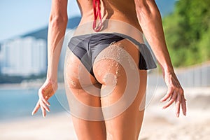 Sporty female in with two sand hand prints. Cropped image of young woman standing her back turned to camera wearing