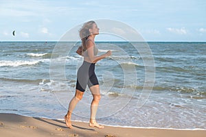 Sporty fit active sexy young blonde woman in sportswear jogging on the beach