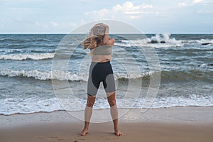 Sporty fit active young blonde caucasian woman stretching on the beach