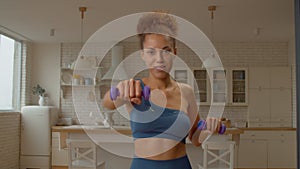 Sporty fit African American woman practicing dumbbell front raise exercise