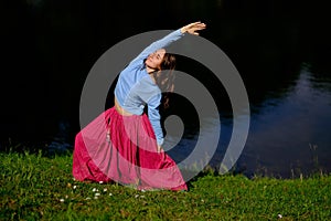 Sporty fit caucasian woman doing asana Virabhadrasana 2 Warrior pose posture in nature.