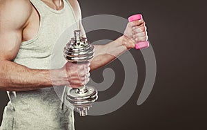 Sporty fit man lifting light and heavy dumbbells.
