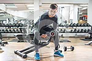 Sporty fit man lifting weights at gym.