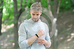 Sporty fit man with sport equipment checks time on smartwatch. Man tracking fitness results dressed in sportswear