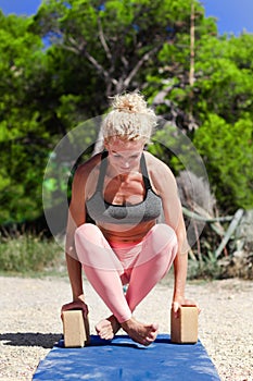 Sporty fit middle aged woman, in upward rooster pose kukkutasana  on tropical beach