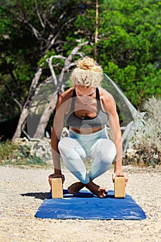 Sporty fit middle aged woman, in upward rooster pose kukkutasana  on tropical beach. Female yoga instructor doing  yoga Outdoor ac