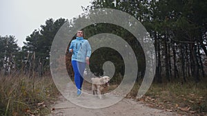 Sporty fit woman with dog jogging in autumn forest