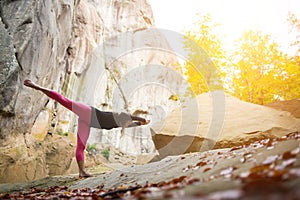 Sporty fit woman is practicing yoga on the boulder in the nature