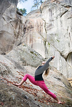 Sporty fit woman is practicing yoga on the boulder in the nature