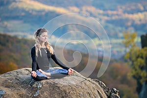 Sporty fit woman is practicing yoga on the top of the mountain