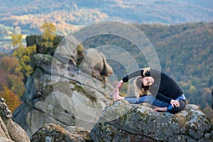 Sporty fit woman is practicing yoga on the top of the mountain